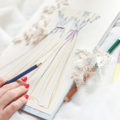 a hand drawing a dress on a sketchbook